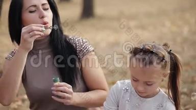一对幸福的母女正在吹肥皂泡.. 在温暖的秋天，<strong>一家人</strong>在城市公园<strong>野餐</strong>